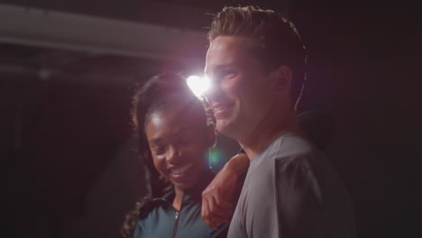 retrato de estudio de una pareja atlética sonriente o amigos en ropa de entrenamiento de fitness disparado en el gimnasio con iluminación de bajo nivel 2