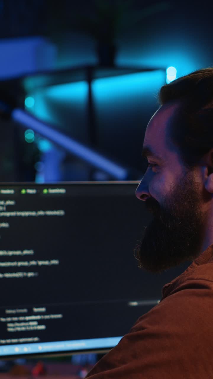 Bearded Man Coding on Computer Screens in Dark Office