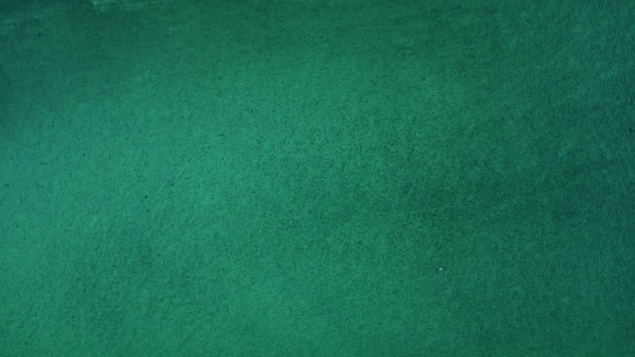 A broad sweep of green-turquoise water reveals gentle shifts in tone and soft underwater textures that create a calm, abstract marine surface shaped by natural light and depth