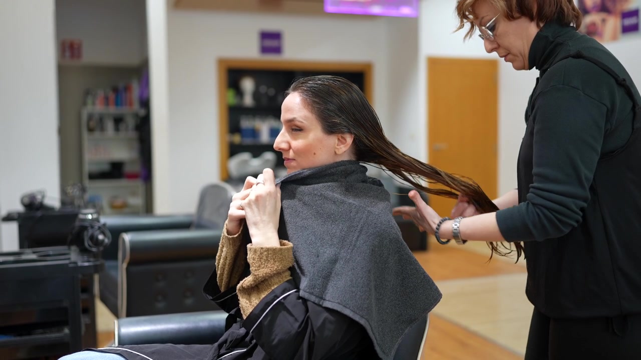 Parrucchiere che prepara la cliente per il taglio di capelli in salone