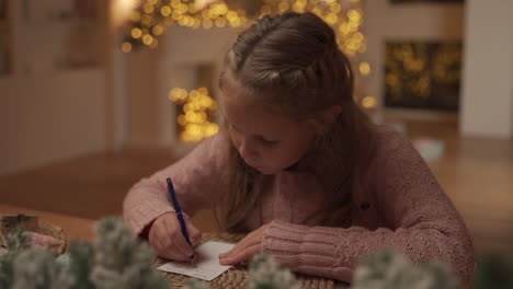 menina escreve uma carta de natal para o papai noel em casa, pensando e sonhando