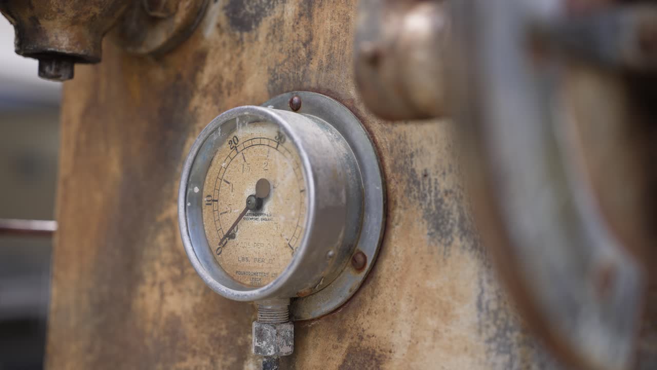 Indicatore industriale d'epoca che mostra una misurazione storica su vecchi macchinari.