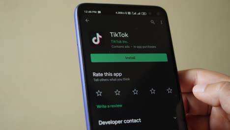 a closeup shot of an android phone indian user displaying the process of uninstalling tiktok application from the google play store.