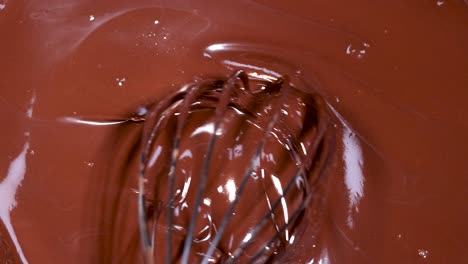 a whisk stirring rich, melted chocolate