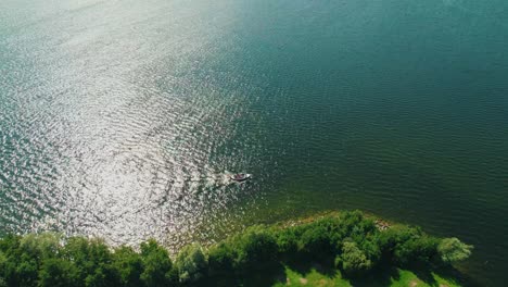 aerial view of small boat sailing near lake bank