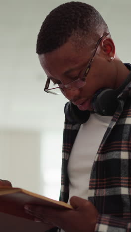 un tipo lee un libro trabajando en la biblioteca de la universidad. un hombre afroamericano visita una librería para conseguir libros de texto para un proyecto educativo. rapta al lector con su novela favorita