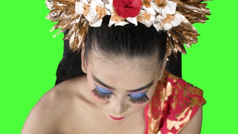 balinese dancer applying lipstick on her lips