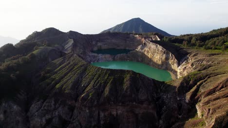 A-breathtaking-drone-shot-of-Kelimutu-Volcano-in-Indonesia,-highlighting-its-vibrant-crater-lakes-and-rugged-terrain