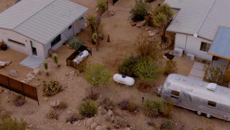 Joshua-Tree-Landschaft-Mit-Einem-Kleinen-Haus-Und-Einem-Bienenstock-Mit-Einer-Neigung-Nach-Unten,-Um-Ein-Haus-Darunter-Und-Einen-Airstream-Anhänger-Freizulegen