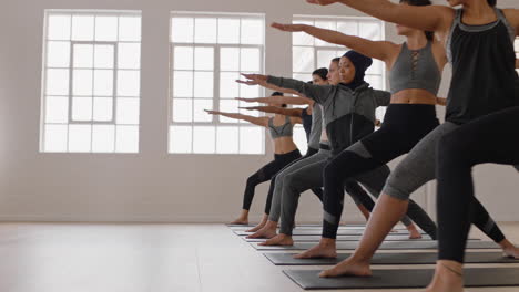 Grupo-De-Clase-De-Yoga-De-Hermosas-Mujeres-Multirraciales-Practican-Pose-Guerrera-Disfrutando-De-Un-Estilo-De-Vida-Saludable-Haciendo-Ejercicio-En-La-Meditación-Del-Gimnasio