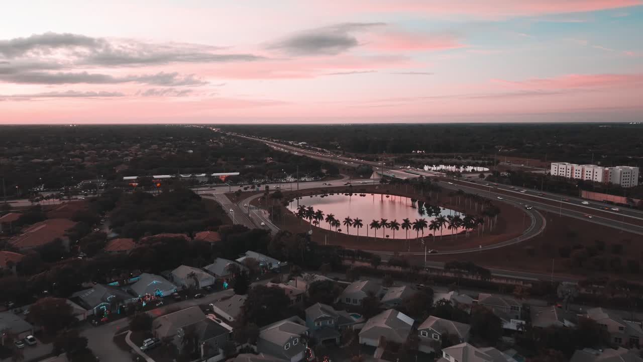 The scene highlights smooth traffic movement, palm-lined curves, reflective water, and modern urban infrastructure, creating a calm yet dynamic city atmosphere