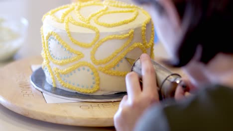 medium shot of cake being frosted over the shoulder of lady baker