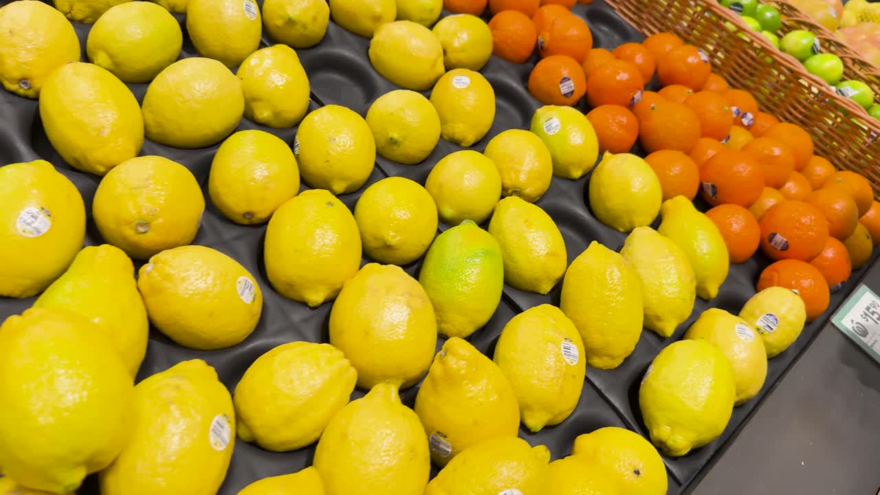 Hand choosing lemons among oranges in store