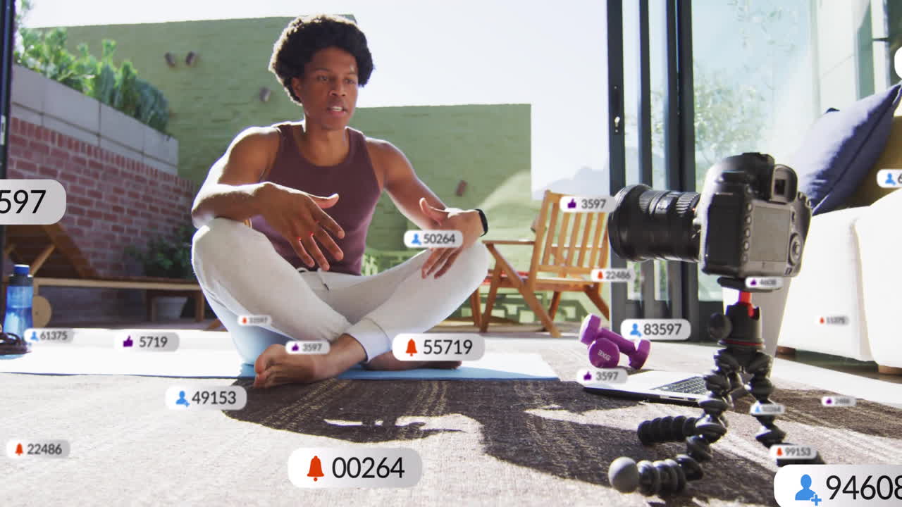 Animation of media icons over biracial man recording video blog