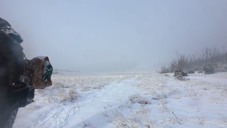 un hombre vestido como un explorador polar lleva un botín en una tormenta de nieve a través de las montañas de australia