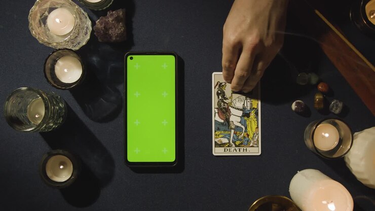 Overhead Shot Of Person Giving Tarot Card Reading With Green Screen Mobile Phone Next To Death Card On Table