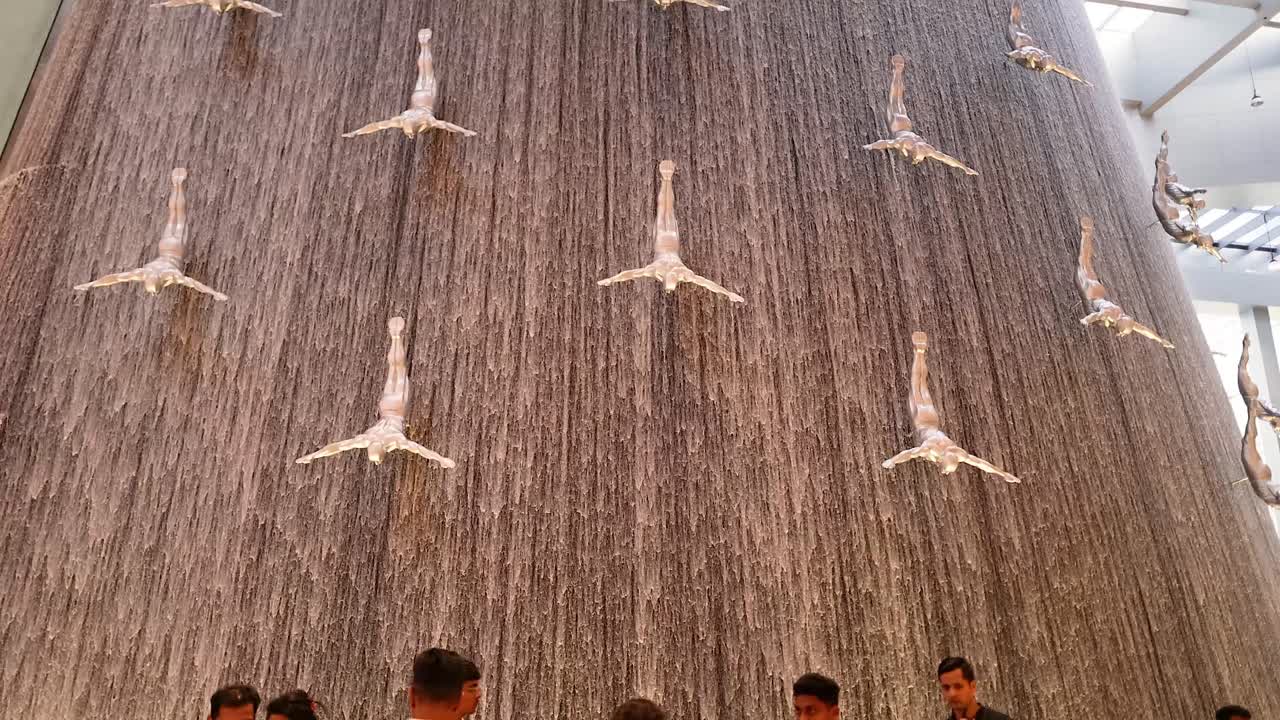 방문객 들 은 다이빙 조각품 을 가진 폭포 를 감상 한다