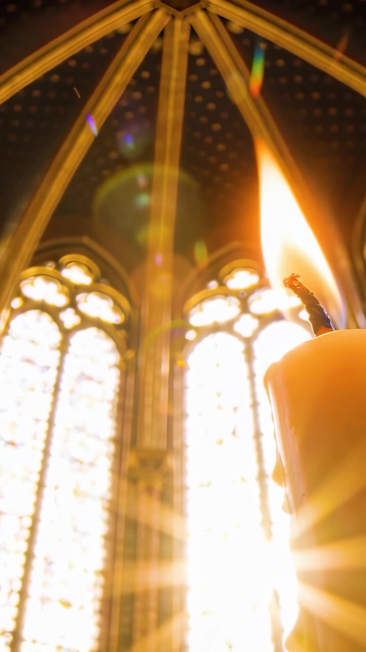 Video verticale: Sole che filtra attraverso le vetrate colorate della chiesa, candela che tremola e sfarfalla, spazio per il testo.