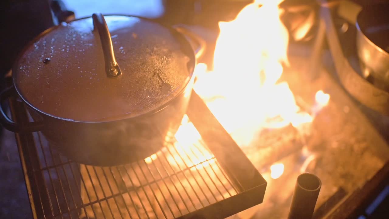 Cooking in a metal pot over an outdoor fireplace, in Lapland, Finland