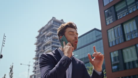 emotional businessman shouting mobile call walking modern district close up.