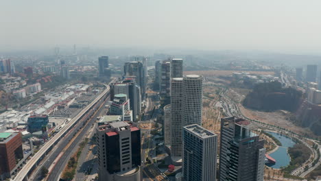 High-angle-view-of-group-of-tall-skyscrapers-in-modern-Santa-Fe-city-part-located-between-multilane-road-and-public-park.-Mexico-City,-Mexico.