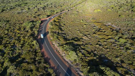 disparo de seguimiento de un autobús turístico que conduce por una carretera rural en amplias tierras verdes
