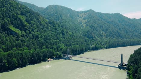 Aerial-Flying-over-a-mountain-river-an-automobile-bridge-people-passing-through-it