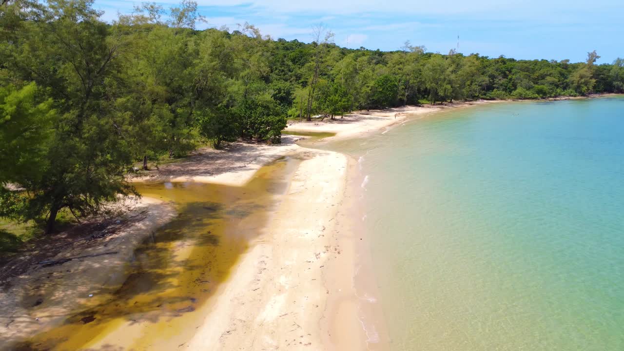 Drone shot moves slowly above a tropical coastline with clear water and empty sand. Filmed at Mpai Bay, Koh Rong Samloem Island near Sihanoukville, Cambodia