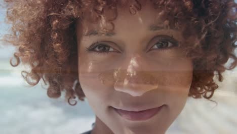 animation of happy biracial woman face over seascape