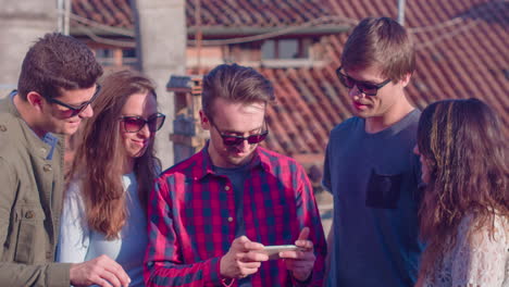 friends sharing a smartphone on a rooftop