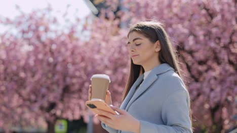 woman enjoying coffee and phone in a spring park