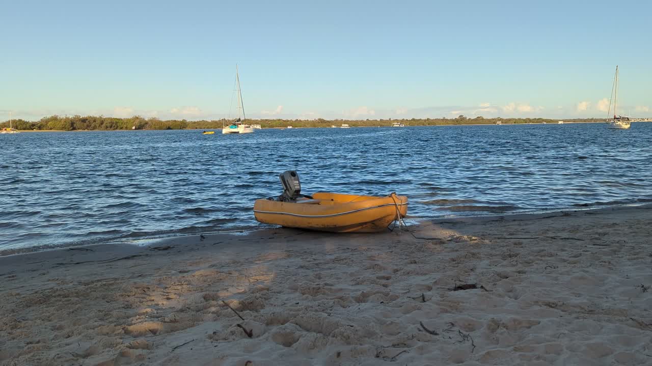 Yellow inflatable boat tied up on the bank of a beach with soft waves rippling the water.
