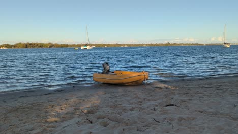 yellow inflatable boat tied up on the bank of a beach with soft waves rippling the water.