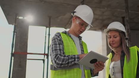 construction worker and engineer talking at construction site site. workers in helmets at building area. portrait of construction engineers working on building site. concept of modern construction