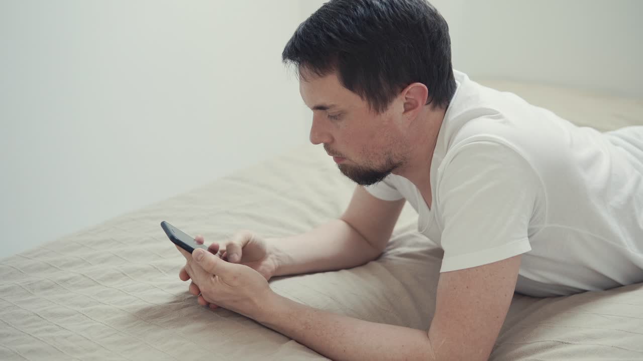 스마트폰을 사용하여 침대에 누워있는 남자