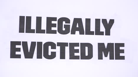 a message on a white cardboard placard says, “illegally evicted me” on a housing protest opposing eviction during the coronavirus pandemic