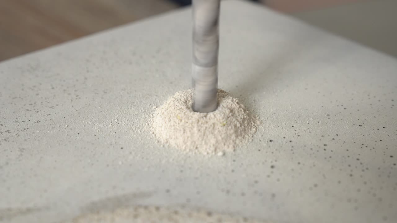 콘크리트에 구멍을 뚫는 금속 드릴과 그 주위에 형성되는 부스러기 더미