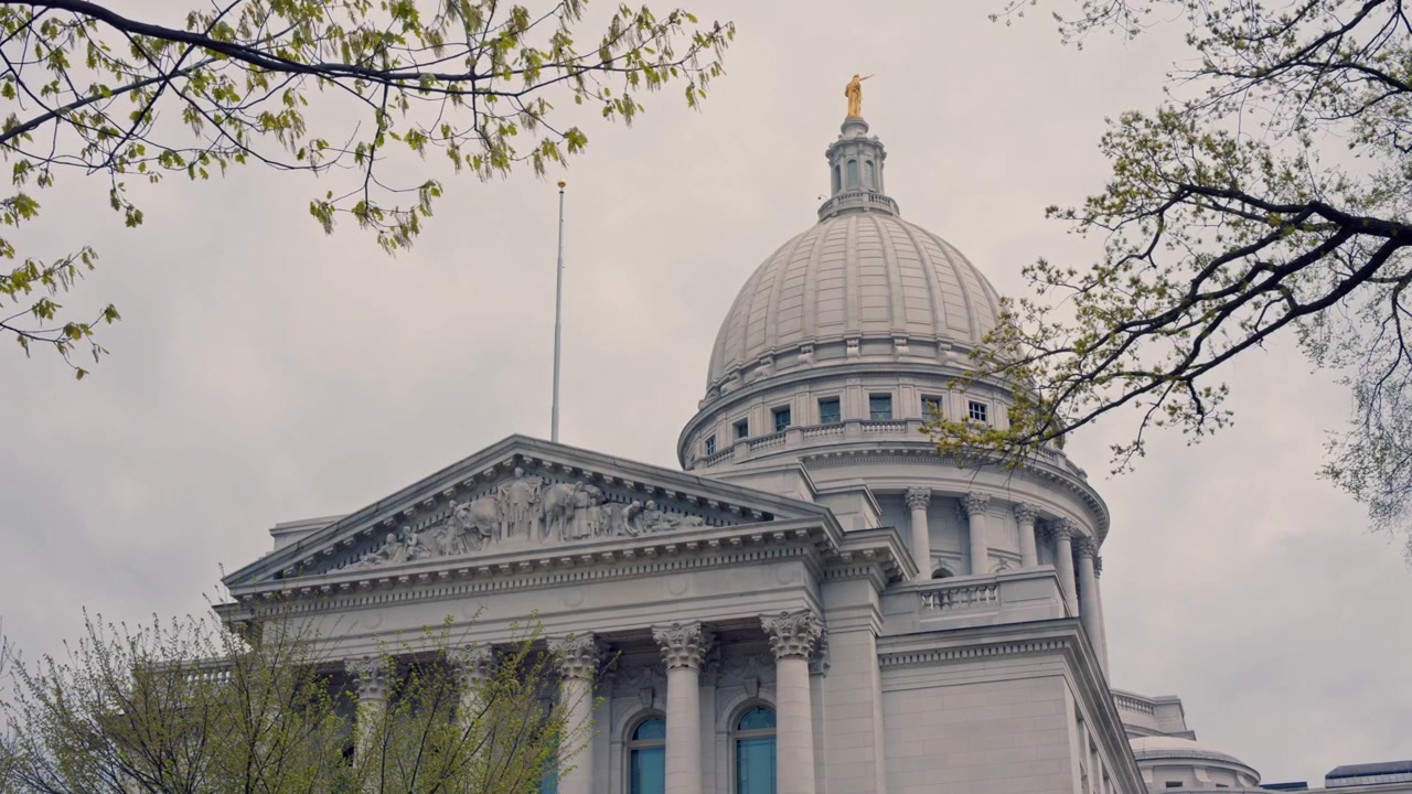 Tomada cinematográfica com gimbal e dolly para a direita do exterior do edifício do Capitólio Estadual de Wisconsin, com movimento de câmera horizontal suave e estabilizado.