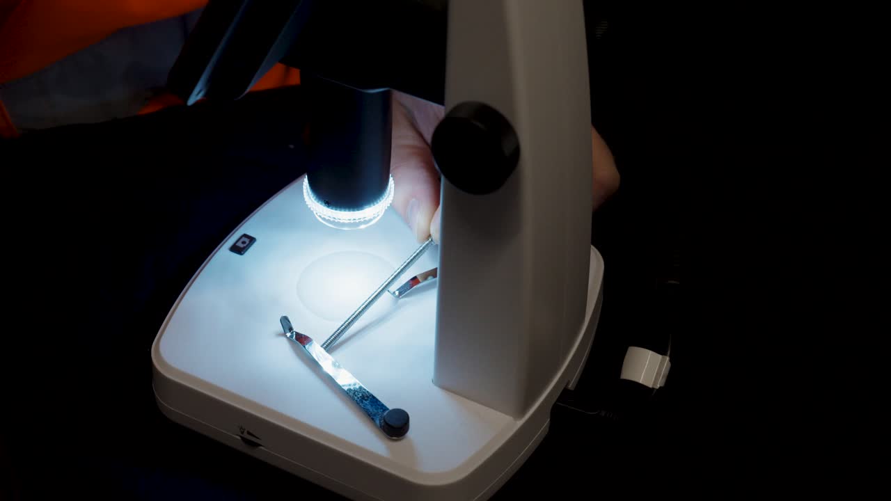 Close-up of a person performing a detailed inspection under a microscope, focusing on precision and accuracy in laboratory or quality control work