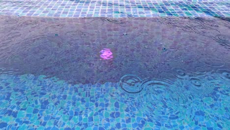 falling raindrops on water surface of blue tiled pool on rainy day in thailand