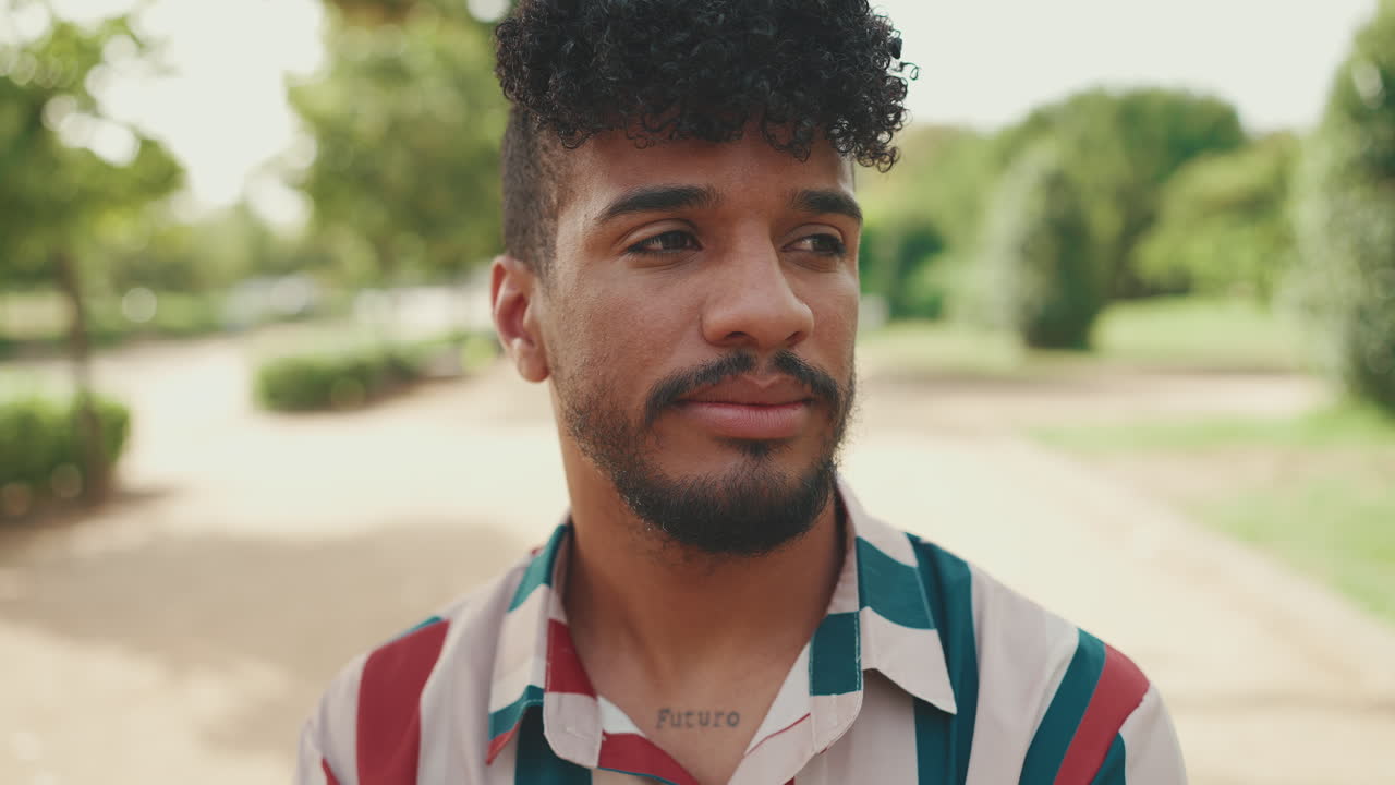 Retrato de um homem com cabelo cacheado e uma tatuagem