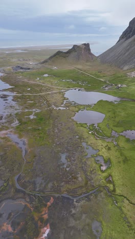 aerial view of viking village set against verdant fields and rocky hills, iceland, vertical shot