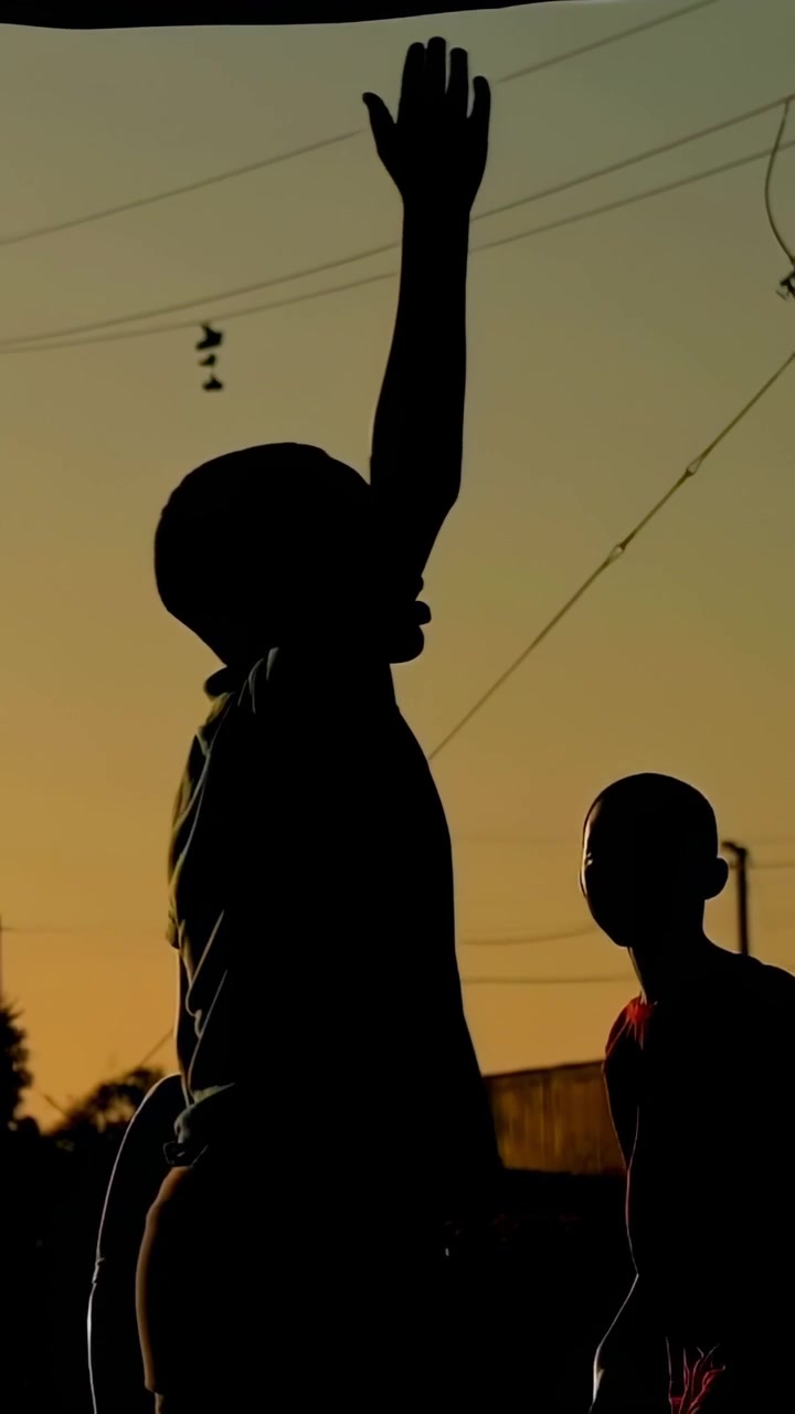 Vertical video: Reaching taller boy stretching up to catch ball tossing upward at sunset with wires