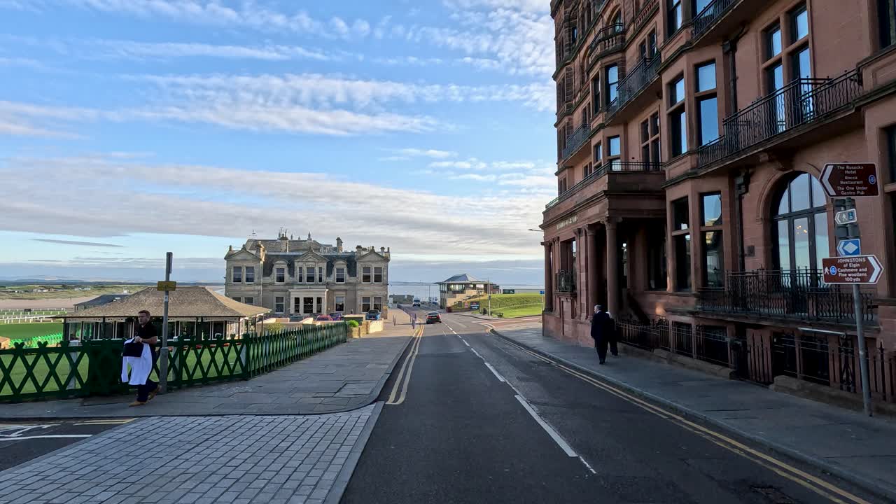 Camera glides down empty stone street toward ocean, classic architecture, soft early morning light