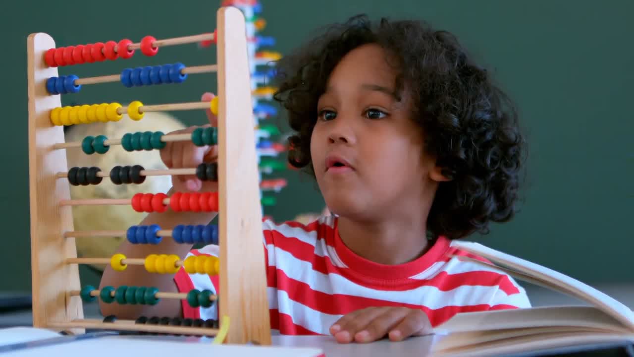 African American schoolboy learning mathematics with abacus at desk in a classroom 4k