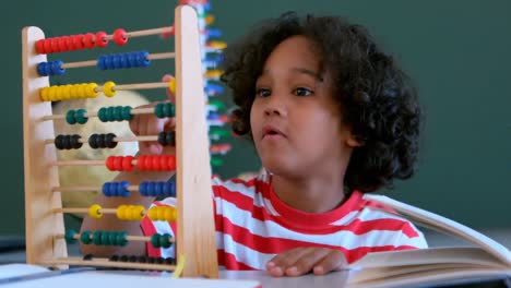 African-American-schoolboy-learning-mathematics-with-abacus-at-desk-in-a-classroom-4k