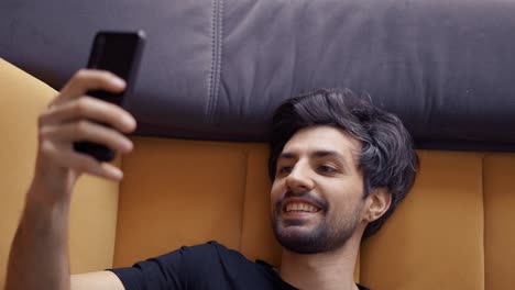 Overhead-view-of-a-man-falls-on-sofa-and-using-a-cell-phone