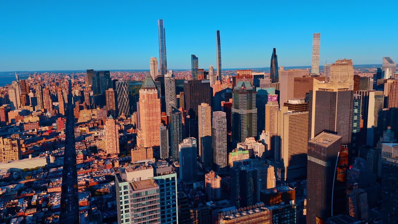 Imponenti grattacieli dello skyline di Manhattan sotto un cielo azzurro e limpido. Veduta aerea che si estende sulla città verso punti di riferimento distanti e complessi edilizi di alto livello.