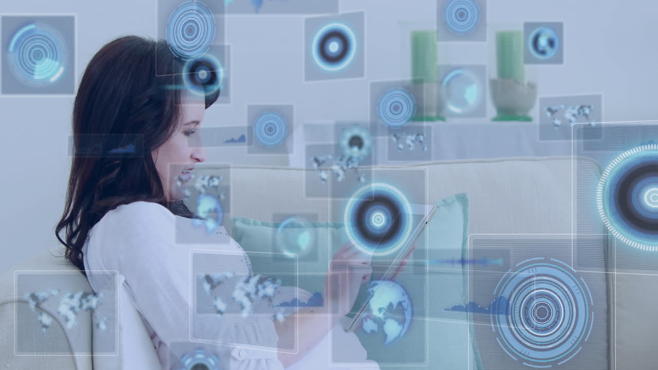 mapas y pantallas de carga de datos sobre una mujer caucásica embarazada en el sofá usando una tableta