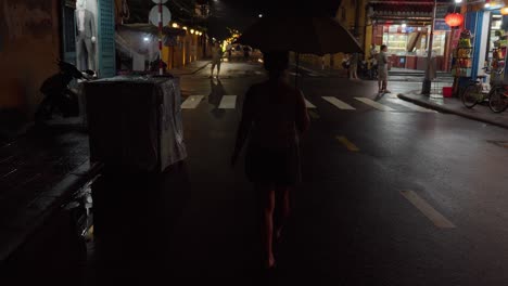 woman walking alone at night in a rainy asian city street